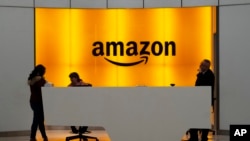 FILE - In this Feb. 14, 2019, file photo people stand in the lobby for Amazon offices in New York.