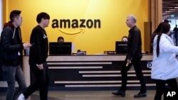 FILE - Employees walk through a lobby at Amazon's headquarters in Seattle, Washington, Nov. 13, 2018.