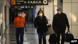 Los pasajeros en el Aeropuerto Internacional San Oscar Romero en San Luis Talpa, El Salvador, usan máscaras faciales como precaución contra la propagación del nuevo coronavirus, COVID-19, el 12 de marzo de 2020. [AFP]