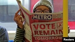 A woman reads a newspaper on the underground in London with a 'vote remain' advert for the BREXIT referendum, Britain June 22, 2016.