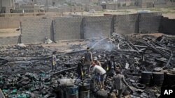 FILE - Workers salvage oil canisters from the wreckage of a vehicle oil store hit by Saudi-led airstrikes in Sanaa, Yemen, July 2, 2020.