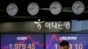 A currency trader talks on the phone near the screens showing the Korea Composite Stock Price Index, left, and the foreign exchange rate between U.S. dollar and South Korean won at the foreign exchange dealing room in Seoul, South Korea, May 25, 2020. 