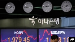 A currency trader talks on the phone near the screens showing the Korea Composite Stock Price Index, left, and the foreign exchange rate between U.S. dollar and South Korean won at the foreign exchange dealing room in Seoul, South Korea, May 25, 2020. 