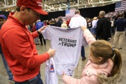 FILE - A supporter of U.S. President Donald Trump looks at a "Veterans for Trump" T-shirt with a young girl at the president's rally in support of Republican candidates on the eve of U.S. midterm elections, in Cleveland, Ohio, Nov. 5, 2018.