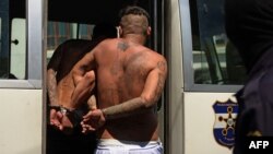 Presuntos integrantes de la pandilla MS-13 abordan un vehículo policial luego de ser presentados a la prensa en San Salvador, el 26 de febrero de 2016.