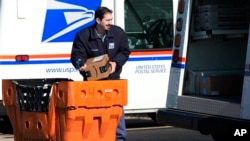 FILE - A U.S. Postal Service employee loads parcels outside a post office in Wheeling, Illinois, Jan. 29, 2024. 