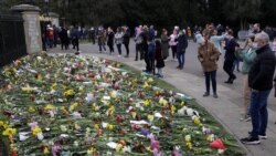 People look at flowers outside Windsor Castle in Windsor, England, to pay tribute to Britain's Prince Philip, the irascible and tough-minded husband of Queen Elizabeth II.