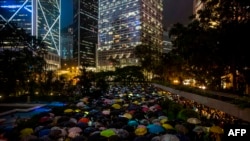 People from the finance community hold umbrellas and shine lights during a protest against a controversial extradition bill in Hong Kong, Aug. 1, 2019. Hundreds of financial workers braved pouring rain, giving that sector's support to protests.