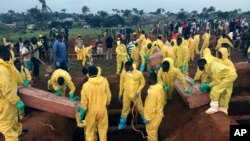 Volunteers handle a coffin during a mass funeral for victims of heavy flooding and mudslides in Regent at a cemetery in Freetown, Sierra Leone, Aug. 17, 2017. 