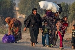 Civilians flee amid Turkish bombardment on Syria's northeastern town of Ras al Ain in the Hasakeh province along the Turkish border, Oct. 9, 2019.