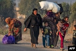 Civilians flee amid Turkish bombardment on Syria's northeastern town of Ras al Ain in the Hasakeh province along the Turkish border, Oct. 9, 2019.