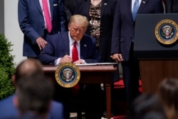 FILE - President Donald Trump signs the Paycheck Protection Program Flexibility Act during a news conference in the Rose Garden of the White House, June 5, 2020.