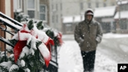 A man walks past snow-covered Christmas decorations on apartments in Berea, Ohio, December 26, 2012. (AP Photo/Mark Duncan)