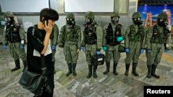 A man using his phone walks past South Korean soldiers wearing protective gears during an anti-biochemical terrorism exercise at a subway station in Seoul, May 7, 2013. 