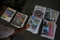 FILE - A Venezuelans picks a newspaper in Caracas, May 1, 2019, after a day of violent clashes on the streets of the capital spurred by opposition leader Juan Guaido's call on the military to rise up against President Nicolas Maduro.