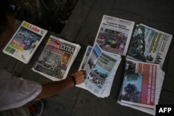 FILE - A Venezuelans picks a newspaper in Caracas, May 1, 2019, after a day of violent clashes on the streets of the capital spurred by opposition leader Juan Guaido's call on the military to rise up against President Nicolas Maduro.
