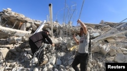 FILE - People look for survivors in the ruins of a hospital hit by missiles in Marat Numan, Idlib province, Syria, Feb. 16, 2016. 