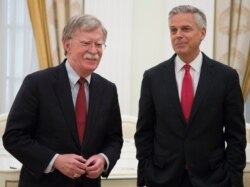 FILE - White House national security adviser John Bolton, left, and U.S. Ambassador to Russia Jon Huntsman wait to begin talks with Russian President Vladimir Putin in the Kremlin in Moscow, June 27, 2018.