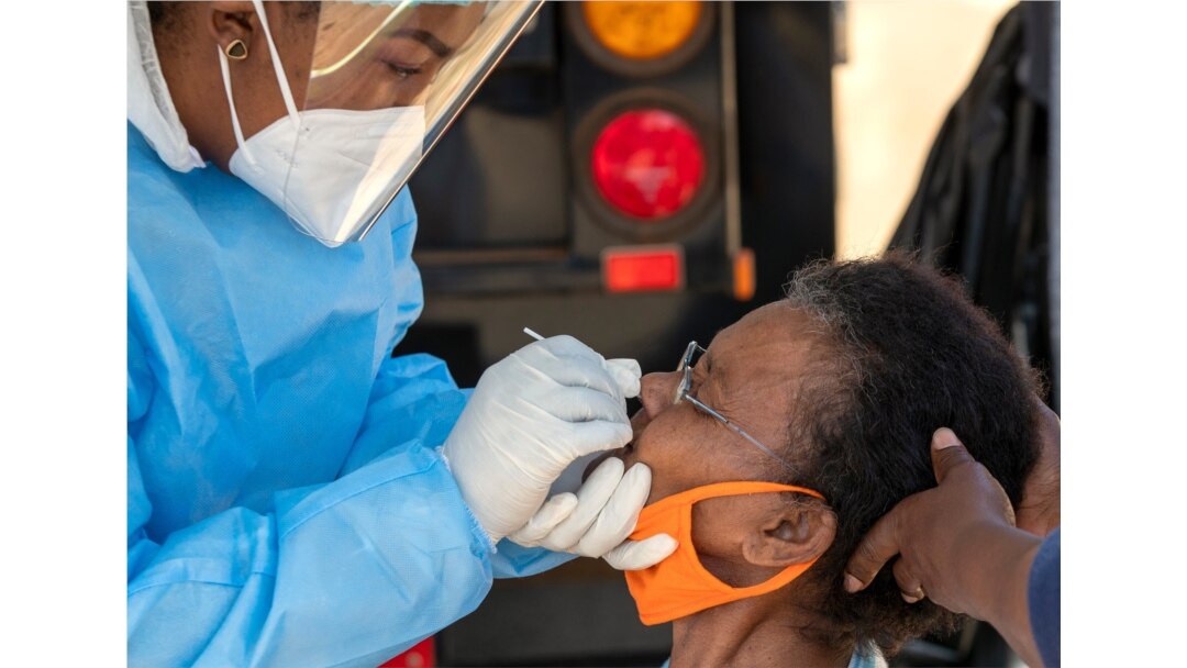 An woman reacts as a heatlh worker collects a sample for coronavirus testing during the screening and testing campaign aimed to combat the spread of COVID-19, in Eldorado Park outside of Johannesburg, South Africa, Aug. 3, 2020.