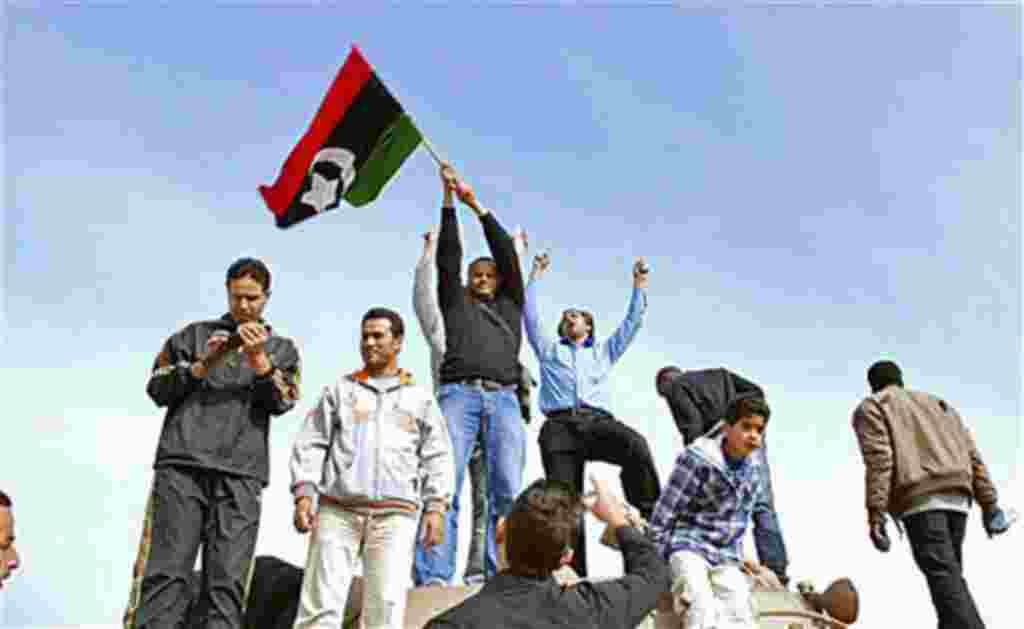 Un grupo levanta una bandera de la era pre-Gadafi en Bengazhi, Libia.