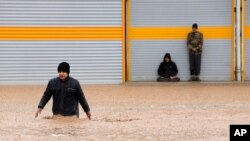 Seorang pria mengarungi jalan yang terendam banjir di Kota Khorramabad di Provinsi Lorestan, bagian barat Iran, 1 April 2019. 