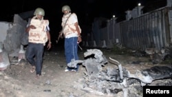 Somali police officers assess the scene of an explosion outside the Jazira hotel in Mogadishu, Jan. 1, 2014. 