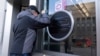 A person looks through the glass as the sign of the U.S. Agency for International Development, or USAID, is seen taped over at the agency headquarters in Washington, Feb. 7, 2025.