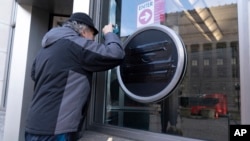 A person looks through the glass as the sign of the U.S. Agency for International Development, or USAID, is seen taped over at the agency headquarters in Washington, Feb. 7, 2025.