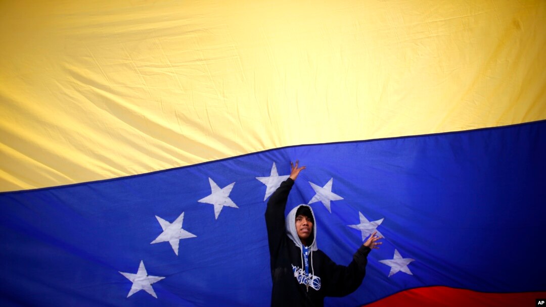 Seorang pemuda mengibarkan bendera Venezuela di tengah jalan ketika oposisi menyerukan jalan-jalan diblokir selama 10 jam di Caracas Venezuela, Senin, 10 Juli 2017.