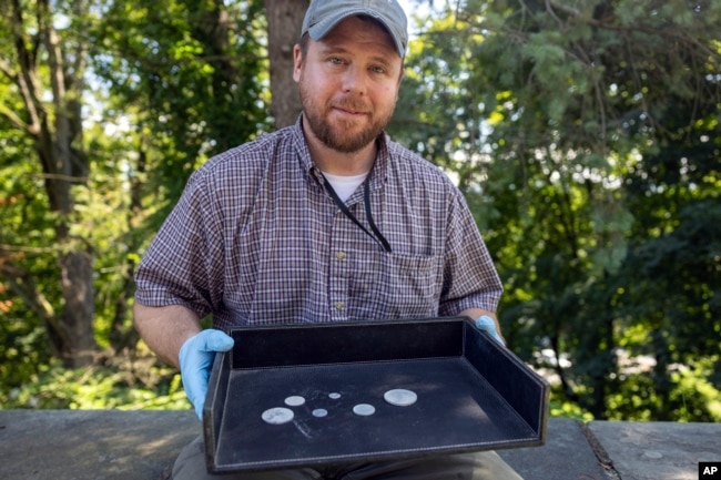 This photo, provided by the U.S. Military Academy at West Point, Aug. 30, 2023, shows West Point archeologist Paul Hudson displaying coins found in the lead box believed to have been placed in the base of a monument by cadets almost two centuries ago, in West Point, NY. (U.S. Military Academy at West Point via AP)