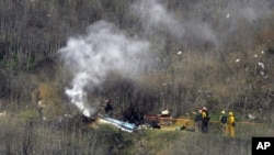 FILE - Firefighters work the scene of a helicopter crash in Calabasas, Calif., Jan. 26, 2020.