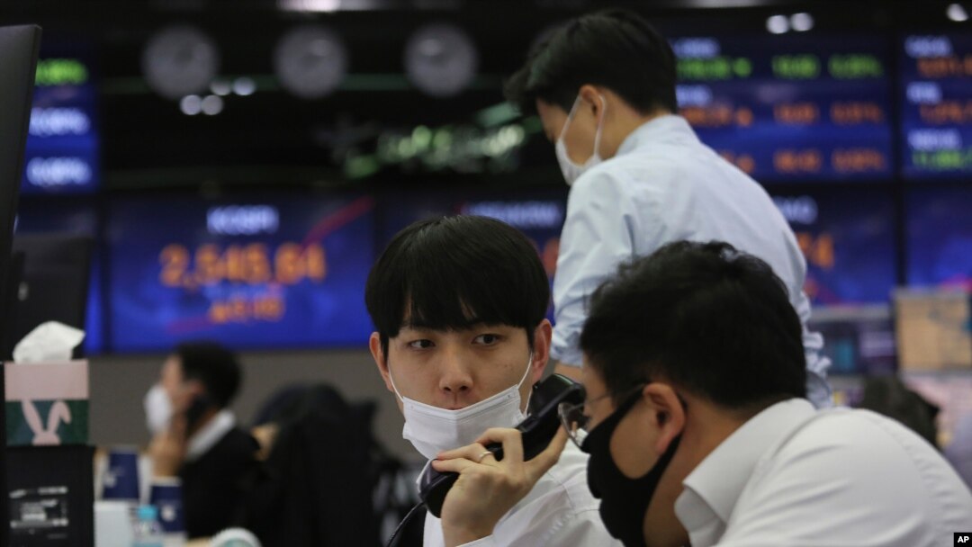 A currency trader talks with his colleague at the foreign exchange dealing room of the KEB Hana Bank headquarters in Seoul, South Korea, Nov. 19, 2020.