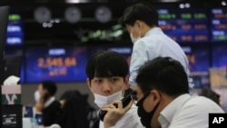 A currency trader talks with his colleague at the foreign exchange dealing room of the KEB Hana Bank headquarters in Seoul, South Korea, Nov. 19, 2020.