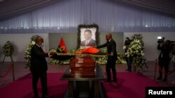 Officials lay a flag on a casket carrying the body of Angola's former President Jose Eduardo dos Santos, who died in Spain in July, as it lies at the Agostinho Neto Memorial in Luanda, August 27, 2022.
