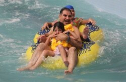 An Iraqi man shares a ride with children at an indoor water park during a heat wave in the capital Baghdad, June 14, 2019.