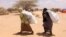 FILE - Southern Somali women carry food aid donations from the UNHCR as they make their way to their refugee camp in Dollow, Somalia, Aug. 30, 2011. Hunger is again stalking the country, and the U.N. is appealing for aid.
