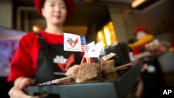 A hostess holds a tray of sliced American beef.