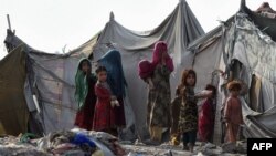 FILE - Children of Afghan refugees play outside tents in the Afghan Basti area on the outskirts of Lahore, Pakistan, June 19, 2021.