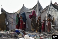 FILE - Children of Afghan refugees play outside tents in Afghan Basti area on the outskirts of Lahore, Pakistan, June 19, 2021.