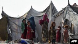 FILE - Children of Afghan refugees play outside tents in Afghan Basti area on the outskirts of Lahore, Pakistan, June 19, 2021.
