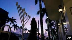 A woman walks past a menorah outside a Jewish synagogue ahead of the start of Hanukkah, in Miami Beach, Florida, on Dec. 1, 2023. A new guide from the Department of Homeland Security aims to help houses of worship protect themselves at a time of heightened tensions in the U.S.