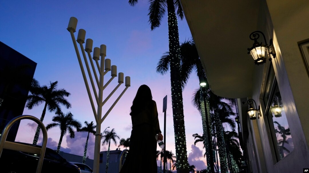 ARCHIVO - Una mujer vestida de forma conservadora pasa junto a una menorá frente a una sinagoga judía antes del inicio de Janucá, en Miami Beach, Florida, el viernes 1 de diciembre de 2023. 