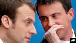 FILE - In this April 8, 2015 file photo, then French Prime Minister Manuel Valls, right, speaks with then Economy Minister Emmanuel Macron in Paris. Presidential hopeful Macron has won the backing of Valls.