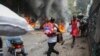 Orang-orang berjalan melewati ban yang terbakar saat protes terhadap Perdana Menteri Haiti Ariel Henry di Port-au-Prince, Haiti, Senin, 5 Februari 2024. (Foto: AP)