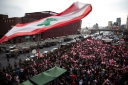 Demonstrators stand next to Lebanese army soldiers during ongoing anti-government protests at a highway in Jal el-Dib, Lebanon, Oct. 23, 2019.