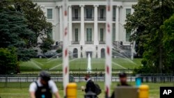 Gedung Putih tampak di belakang sementara paspampres berjaga di pos pemeriksaan di Constitution Avenue, Washington DC, 2 Juni 2020. (Foto: AP)