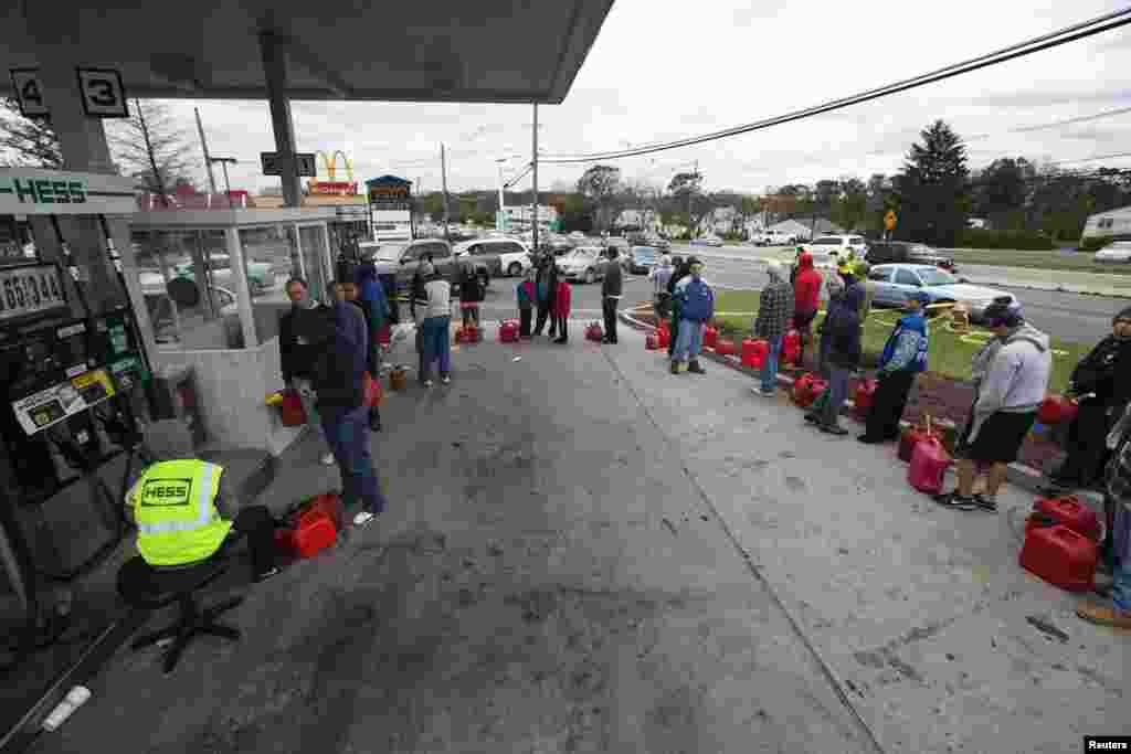 ຢູ້ຄົນໄດ້ຮັບຜົນກະທົບຈາກໄຟຟ້າມອດ ຍ້ອນລົມພາຍຸເຮີຣີເຄນ Sandy ລຽນຄີວຖ້າກັນເປັນສອງແຖວ ທີ່ປໍ້ານໍ້າມັນແຫ່ງນຶ່ງ ເພື່ອຊື້ນໍ້າມັນໄປໃສ່ຈັກປັ່ນໄຟຟ້າຢູ່ເຂດ Madison Park, ລັດນີວເຈີຊີ ໃນວັນທີ 31 ຕຸລາ, 2012. 