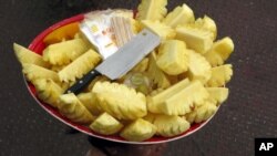 FILE - A vendor carries pieces of pineapple on her head during business at a jetty in Yangon, Myanmar.