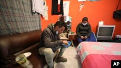 La migrante venezolana Yaquelin Timaure, derecha, acompaña a su pareja Richard Luzardo, mientras almuerza en su casa en Bogotá, Colombia, el lunes 21 de diciembre de 2020.