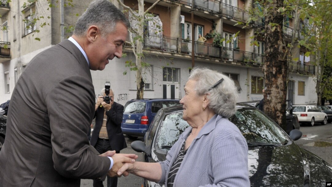 FILE - Montenegrin leader Milo Djukanovic talks to a supporter in front of a polling station in downtown Podgorica, Oct. 14, 2012.